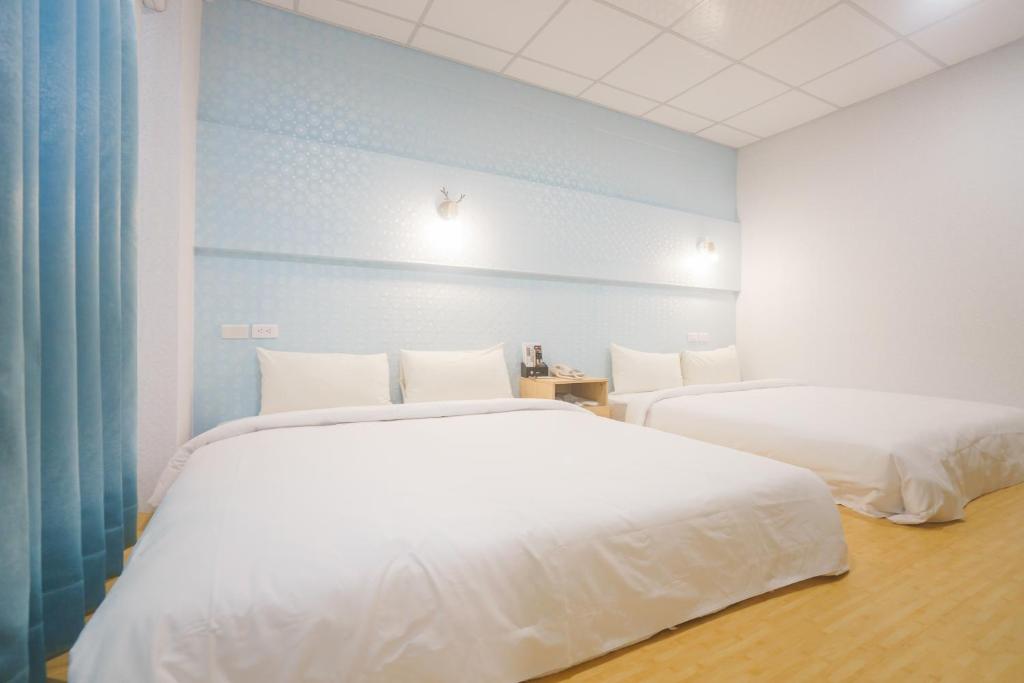 two white beds in a room with blue walls at The Riverside Hotel Fashion in Kaohsiung