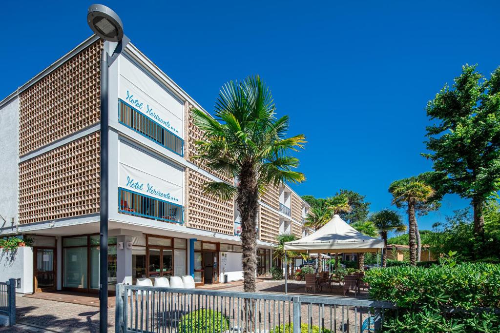 un bâtiment avec un palmier en face dans l'établissement Hotel Horizonte, à Bibione