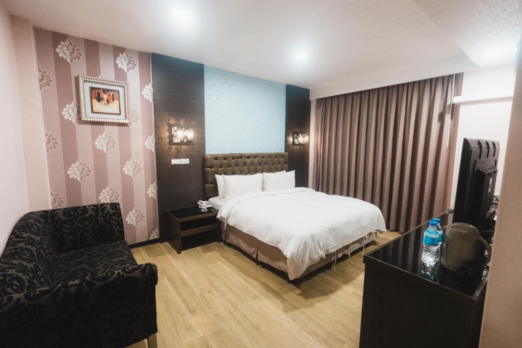 a hotel room with a bed and a chair at The Riverside Hotel Fashion in Kaohsiung