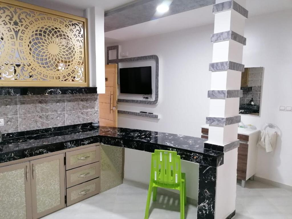 uma cozinha com um balcão preto e um banco verde em Appartement lux dakhla em Dakhla