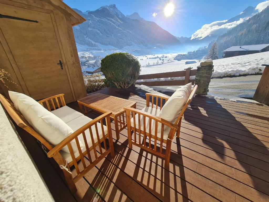 2 Stühle und ein Tisch auf einer Terrasse mit einem verschneiten Berg in der Unterkunft klein&fein in Neustift im Stubaital