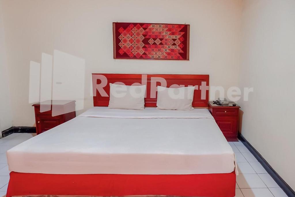 a bedroom with a red and white bed in a room at Graha Sartika Hotel RedPartner in Bandung