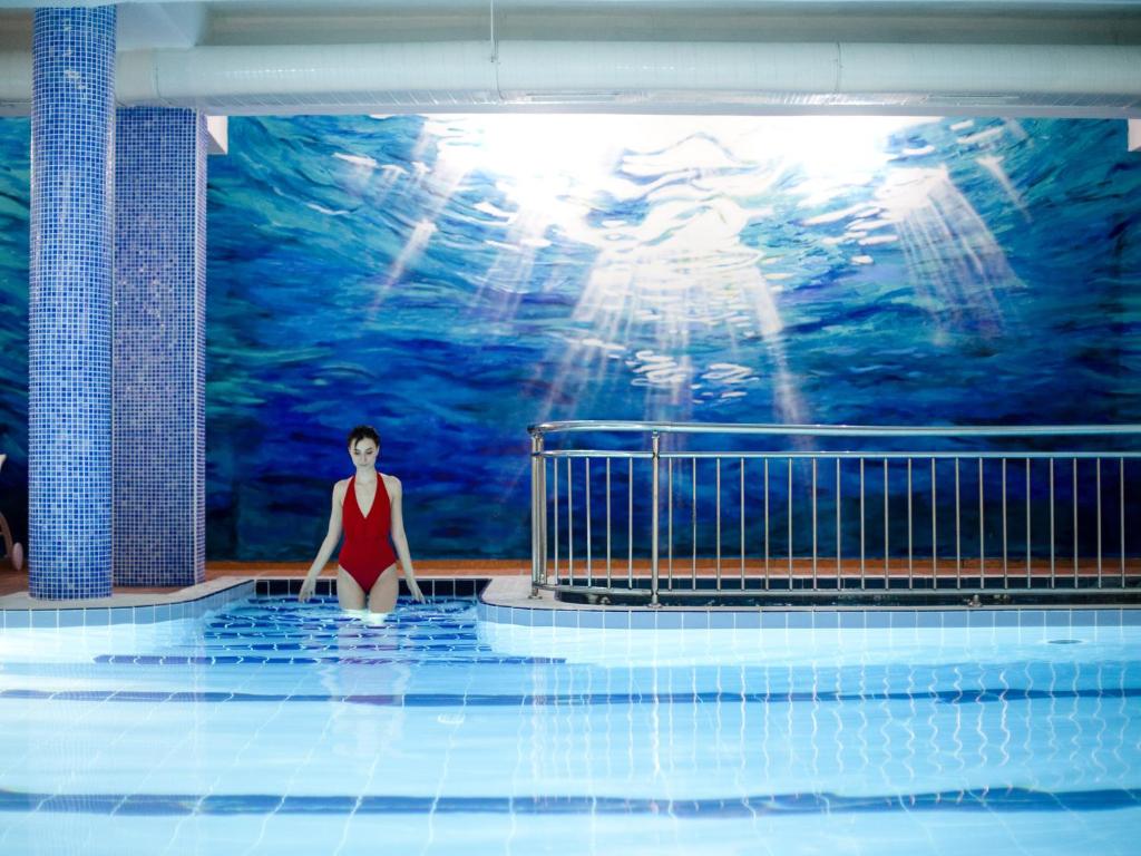 Una mujer con un vestido rojo parada en una piscina en Hotel Monec, en Ankara