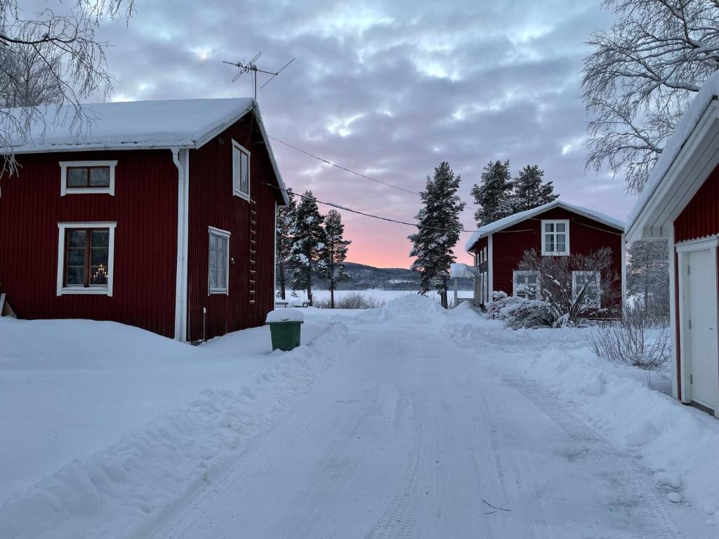 une route enneigée à côté d'une grange rouge dans l'établissement Trevlig villa mellan sjöarna i Vistträsk By., à Vistheden