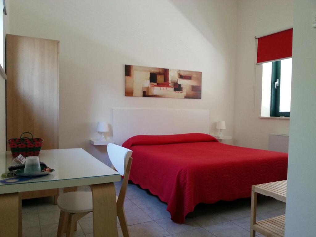 1 dormitorio con cama roja y mesa en Bambù Affittacamere & Residence, en Teramo