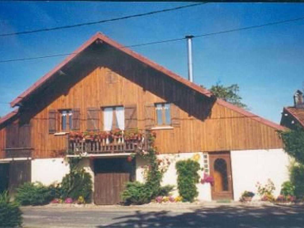 ein großes Holzhaus mit Balkon davor in der Unterkunft Gîte nature, 15 km de Gérardmer, randonnée, ski, jardin, terrasse, BBQ, équipements bébé inclus - FR-1-589-64 in Champdray