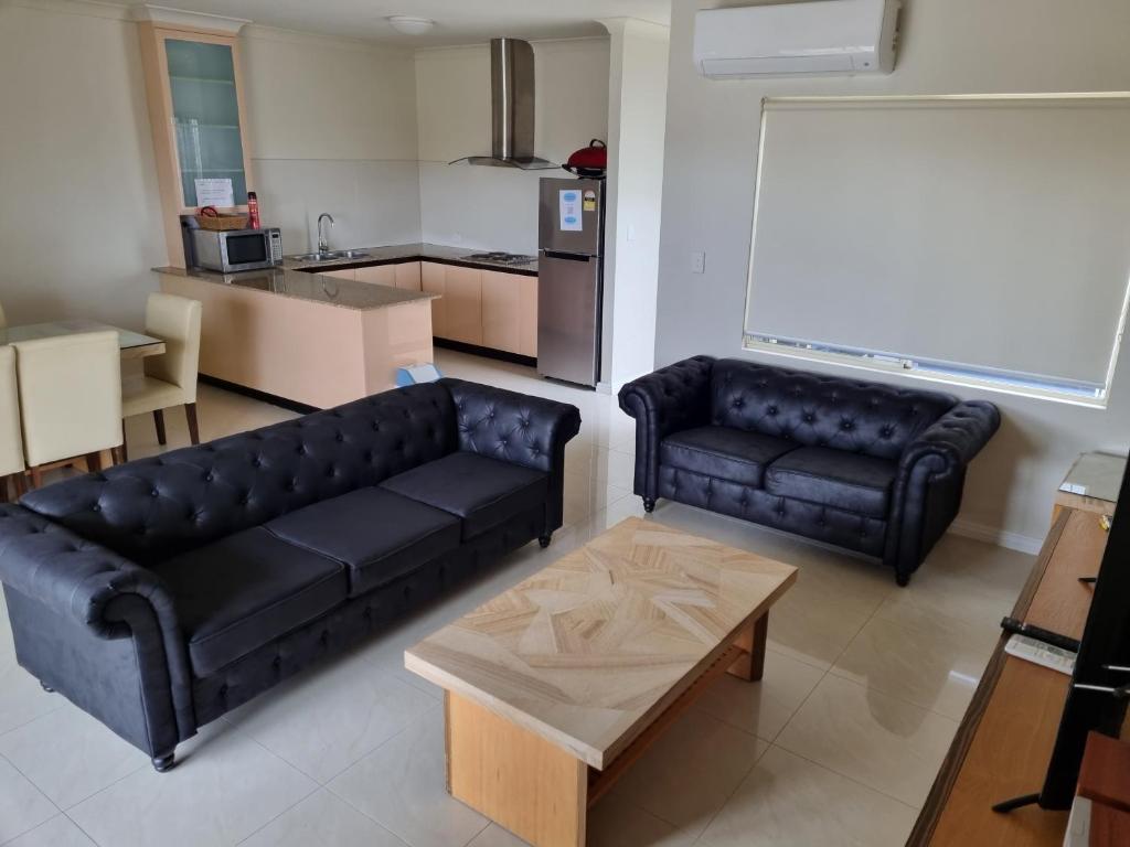 a living room with two black couches and a kitchen at Seafront Unit 60 in Jurien Bay