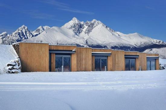 a building in front of a snow covered mountain at Natur Resort in Veľká Lomnica