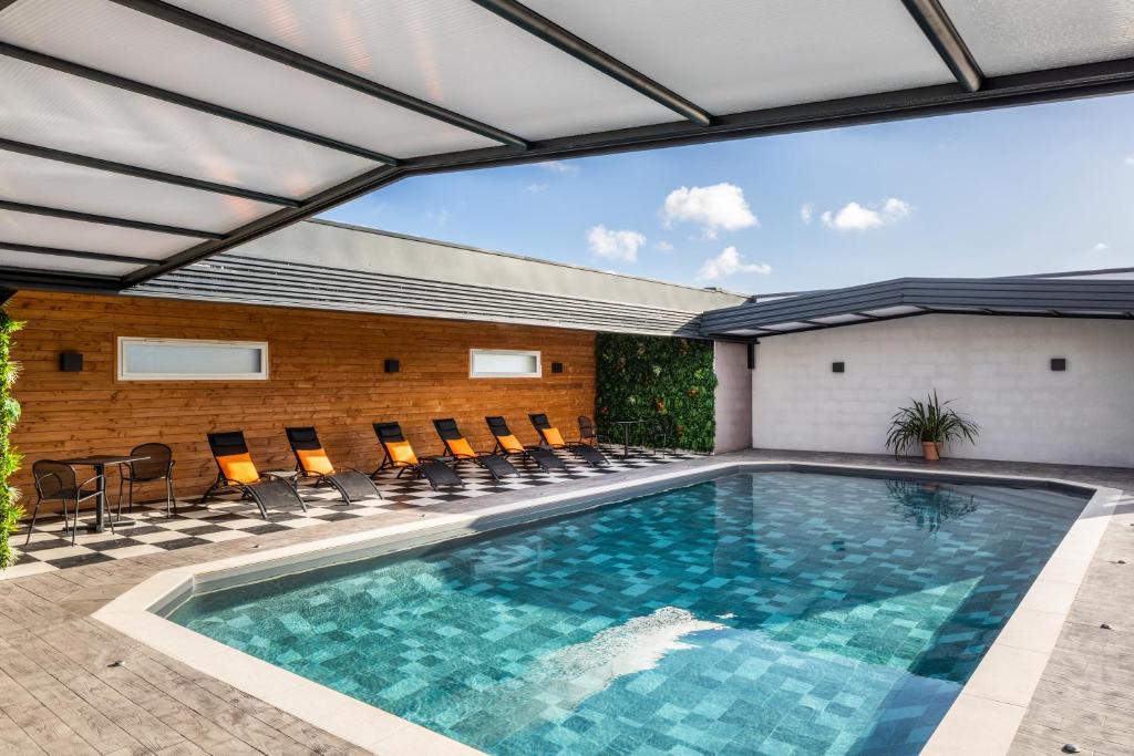 une piscine intérieure avec des chaises et un bâtiment dans l'établissement ibis Saint-Nazaire - Trignac, à Trignac