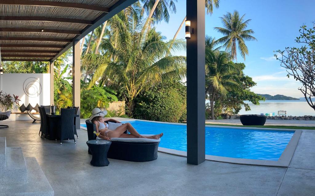 a woman sitting in a chair next to a swimming pool at Bliss Villas in Srithanu