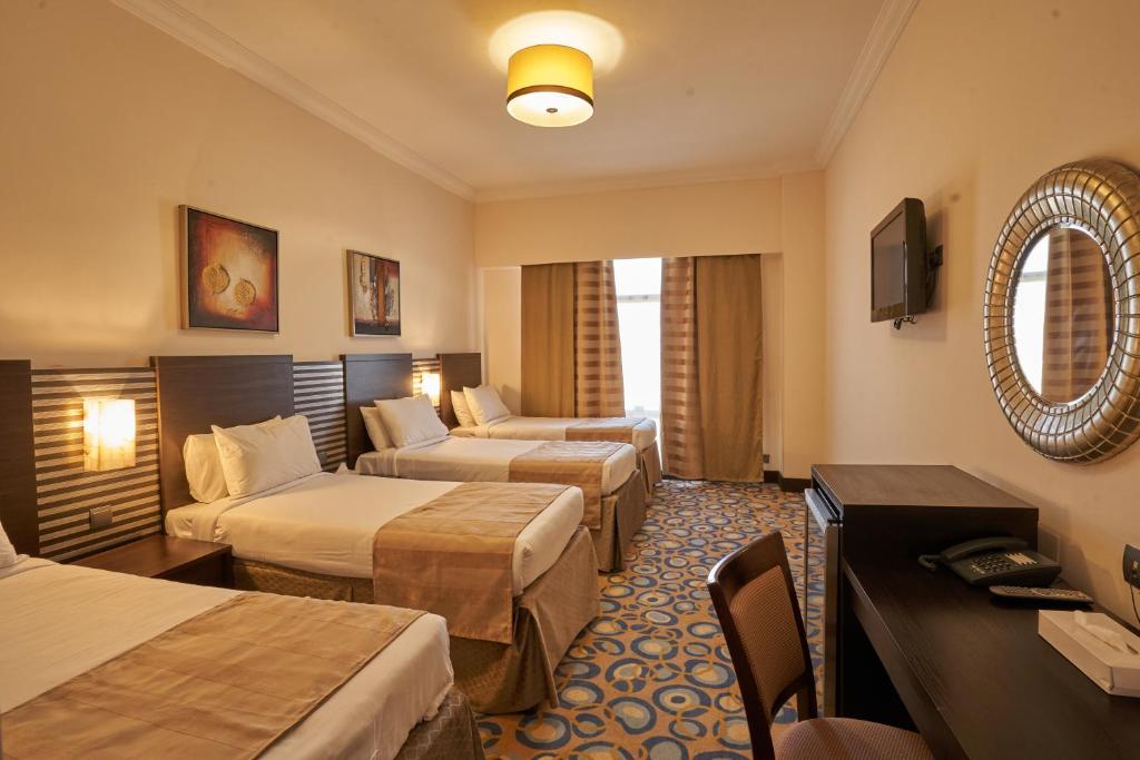 a hotel room with two beds and a living room at Al Hidayah Towers Hotel in Makkah