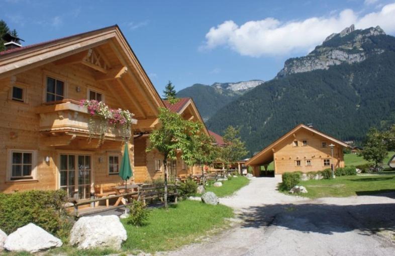 un groupe de bâtiments avec des montagnes en arrière-plan dans l'établissement Achenseer Hüttendörfl, à Maurach