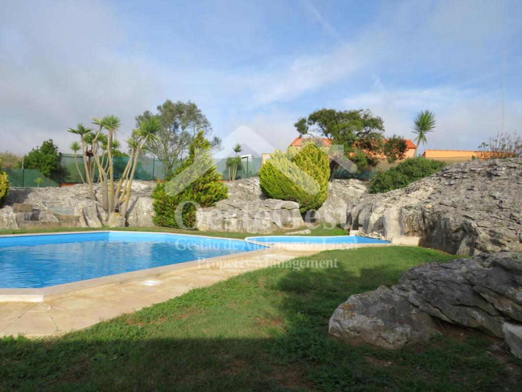 una piscina en un patio con una pared de roca en Villa Arrifes, en Reguengo Grande