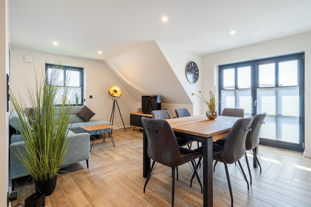 een woonkamer met een tafel en stoelen en een bank bij Vista 5, mit Balkon und drei Schlafzimmern in Greetsiel