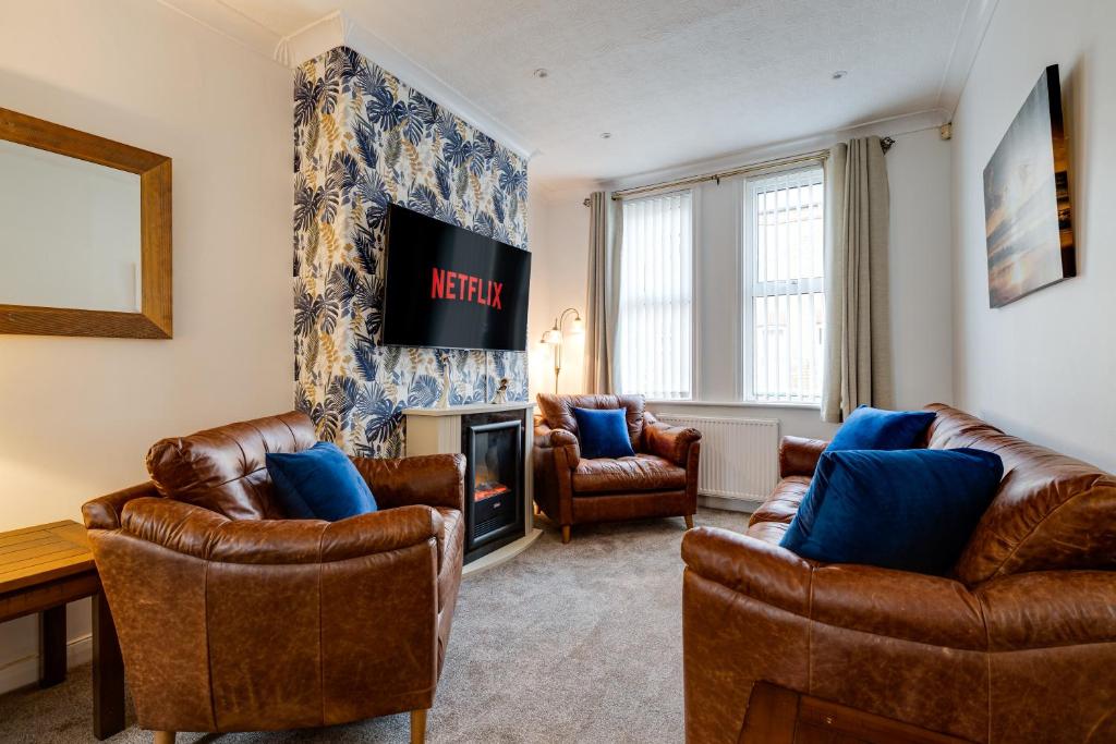 a living room with leather furniture and a television at Sandy House in Scarborough