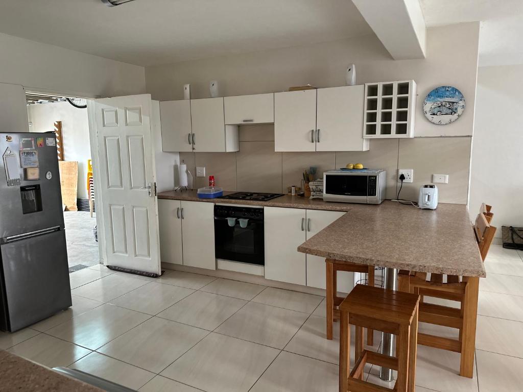 a kitchen with white cabinets and a table and a refrigerator at Sandy Shores 3 Henties in Hentiesbaai