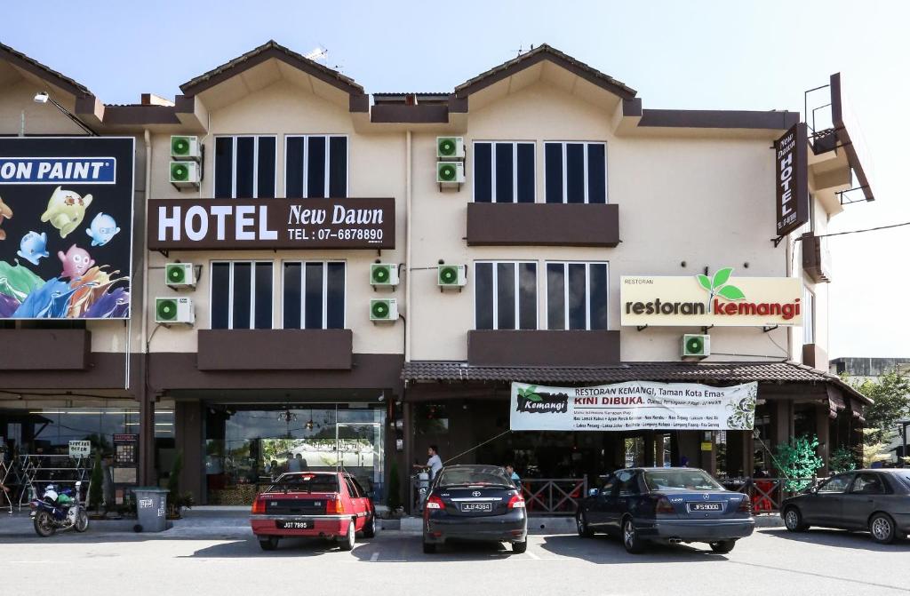 un hôtel avec des voitures garées devant lui dans l'établissement New Dawn Hotel Pontian Sdn Bhd, à Pontian Kecil
