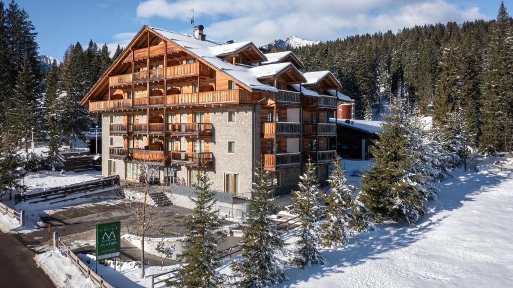 a large building in the snow with trees at Maribel Hotel in Madonna di Campiglio