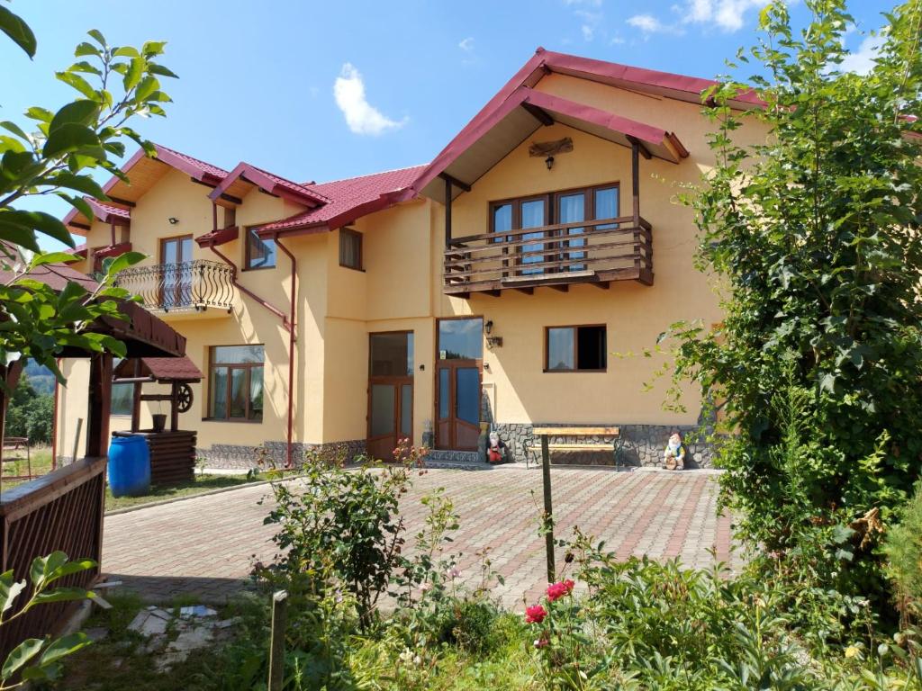 uma casa com uma varanda e um quintal em Casa de vacanta La Ticu em Cîndeşti