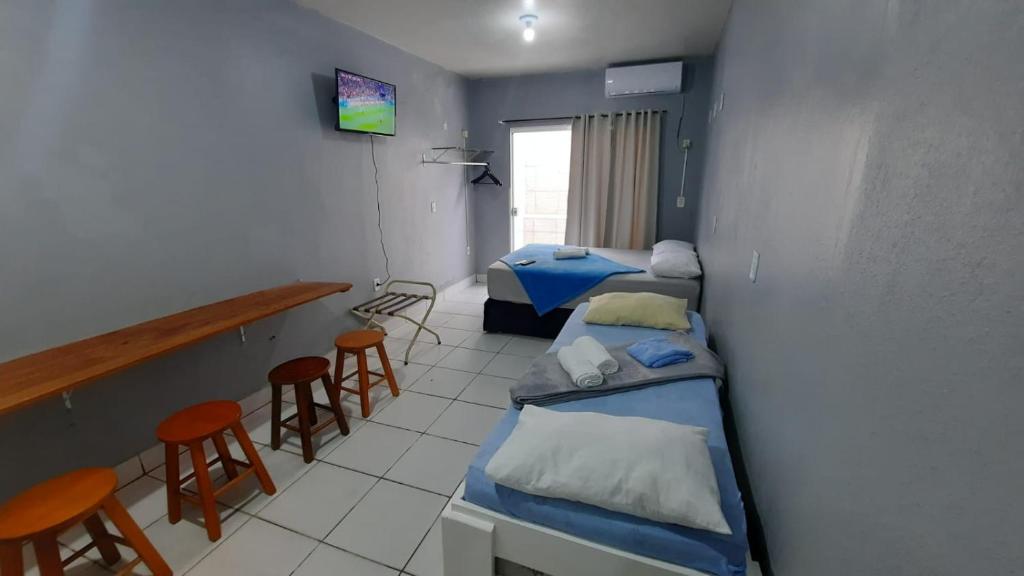 una habitación con 3 camas y un bar con taburetes en Estúdios Individual na Meia Praia ar, wifi, vaga, cozinha, tv smart - 6 x no cartão sem juros, en Itapema
