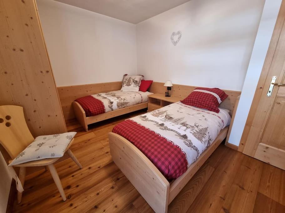 1 dormitorio con 2 camas y 1 silla en Appartamento ai larici, rustico ed elegante en Varena