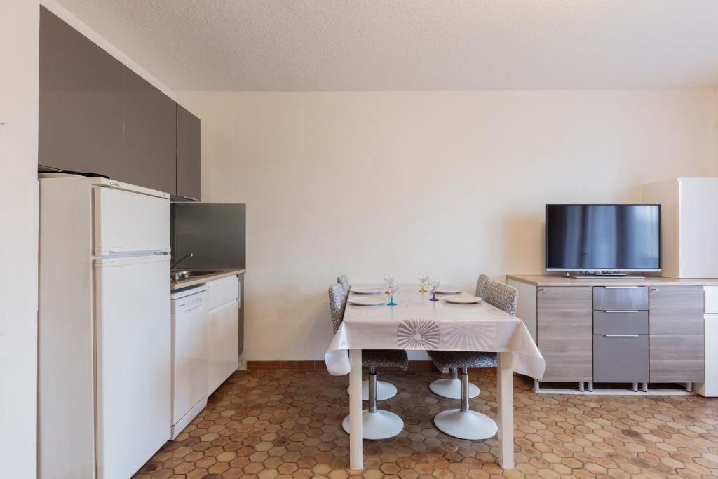 a small kitchen with a table and a refrigerator at Les Narcisses - aux pieds des pistes in Saint-Léger-les-Mélèzes