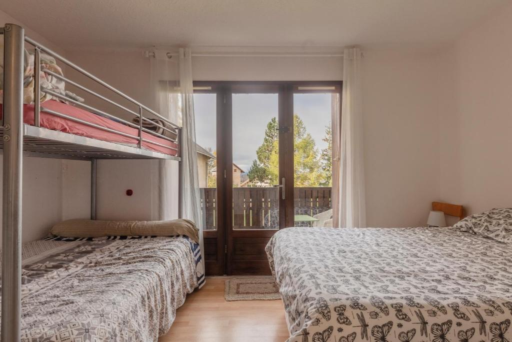 1 dormitorio con 2 camas y balcón en Les Narcisses - aux pieds des pistes, en Saint-Léger-les-Mélèzes