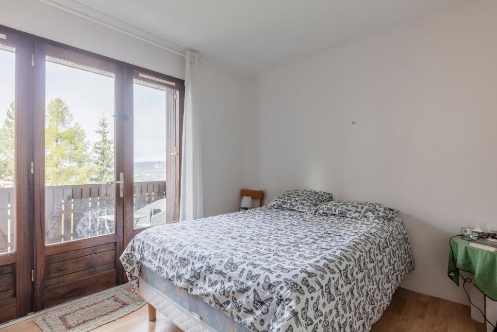 a bedroom with a bed and a large window at Les Narcisses - aux pieds des pistes in Saint-Léger-les-Mélèzes