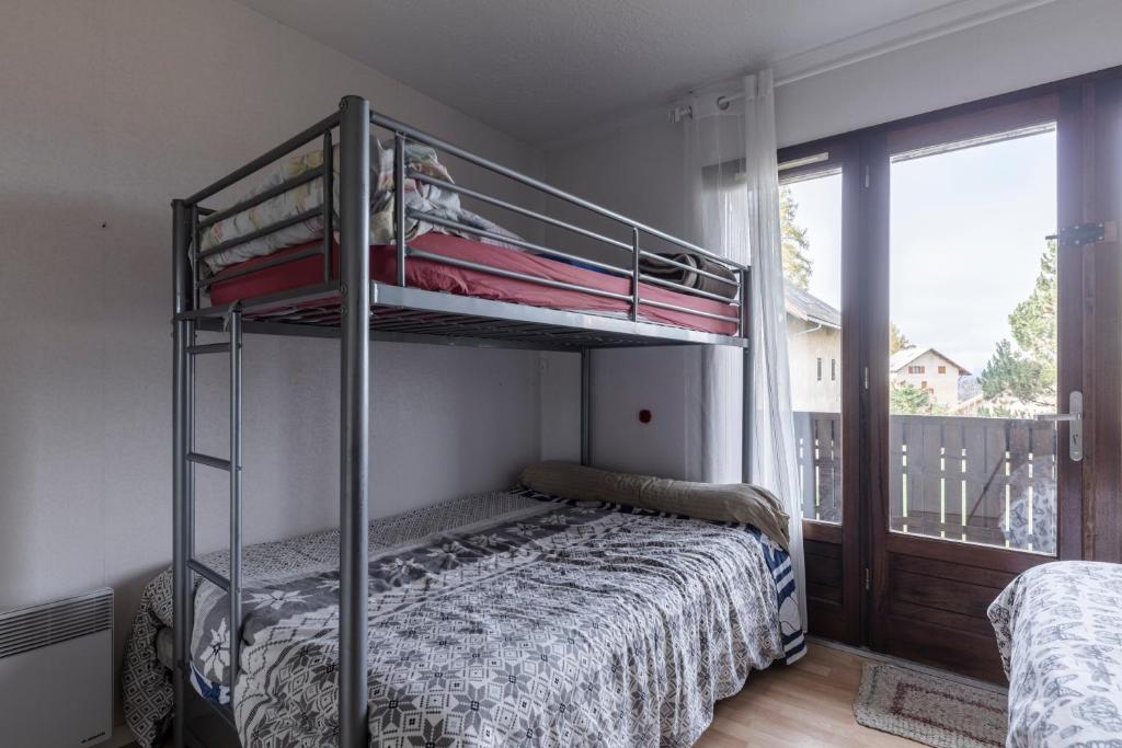 a bedroom with a bunk bed and a balcony at Les Narcisses - aux pieds des pistes in Saint-Léger-les-Mélèzes