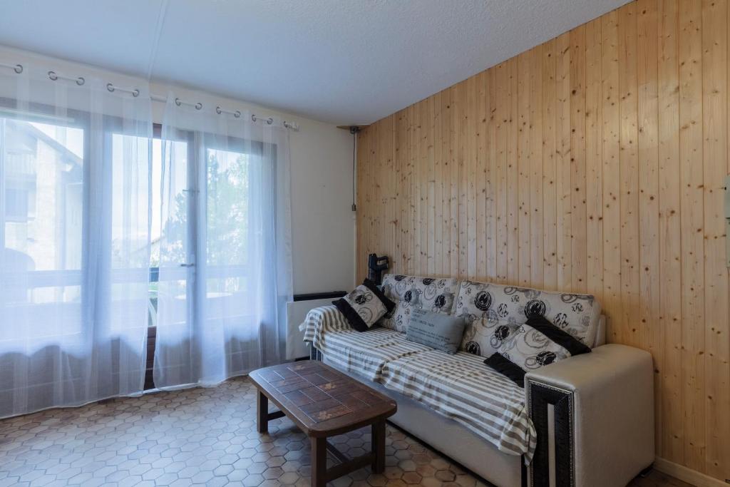 a living room with a couch and a window at Les Narcisses - aux pieds des pistes in Saint-Léger-les-Mélèzes