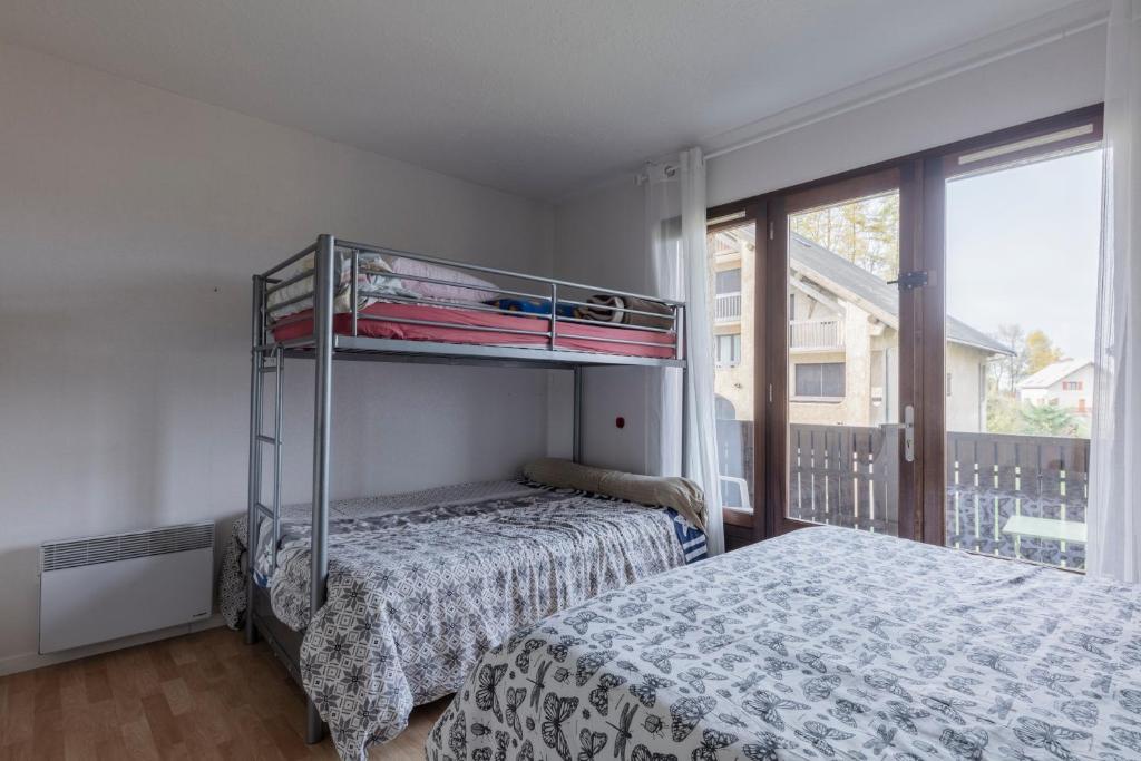 a bedroom with a bunk bed next to a window at Les Narcisses - aux pieds des pistes in Saint-Léger-les-Mélèzes