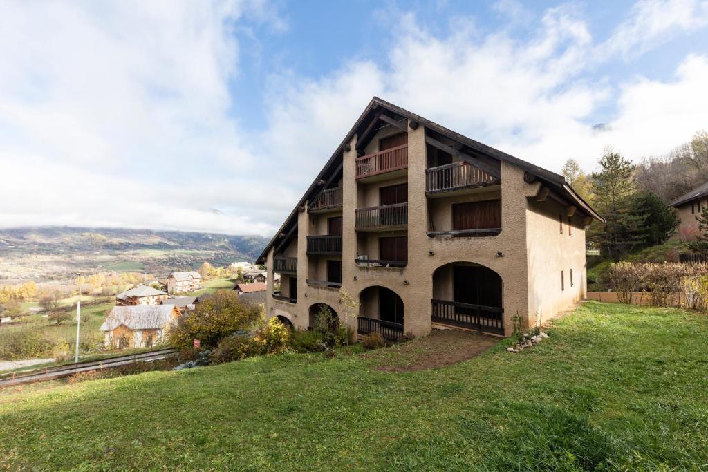 a building on top of a grassy hill at Les Narcisses - aux pieds des pistes in Saint-Léger-les-Mélèzes