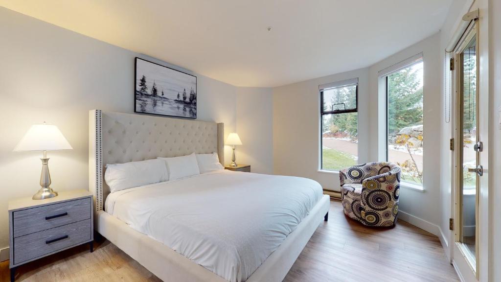 a bedroom with a white bed and a window at Ironwoods on Blueberry Hill by Whistler Blackcomb Vacation Rentals in Whistler