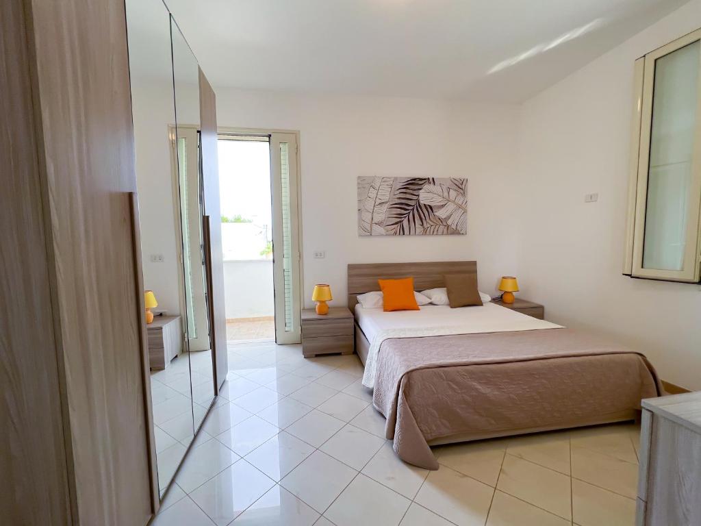 Casa Dell'Abate في كاسالابات: غرفة نوم مع سرير مع وسائد برتقالية ومرآة