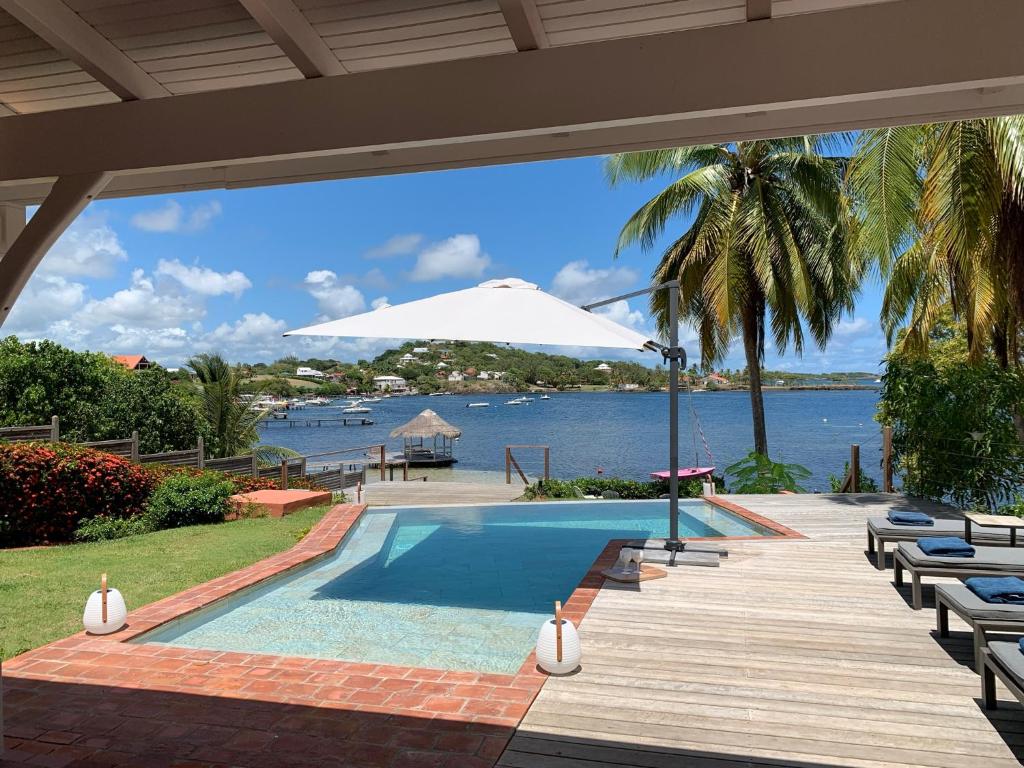- une piscine avec une terrasse et un parasol dans l'établissement Villas Manzelle - Luxury villas on the beach, au Vauclin