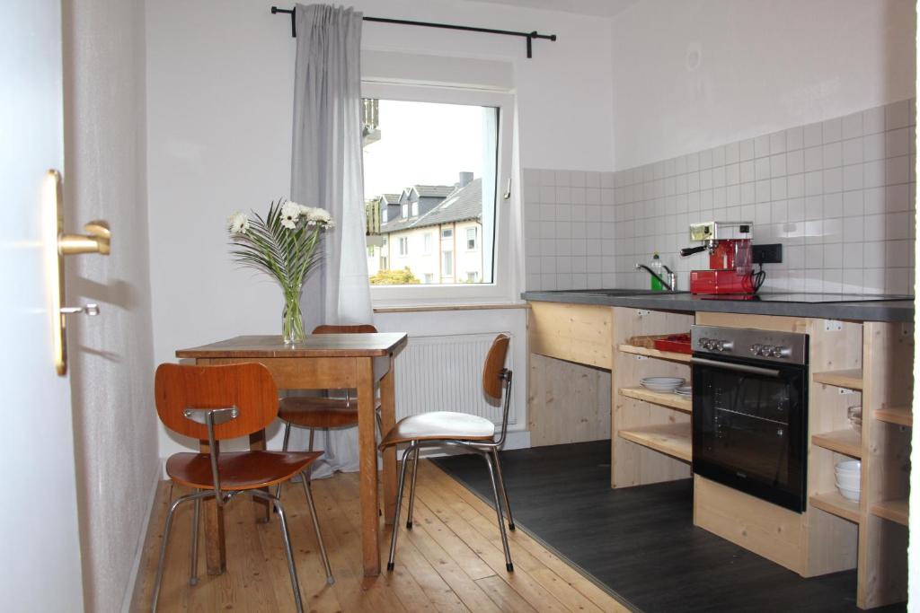 cocina con mesa, sillas y ventana en Apartment Wostspitze en Bochum