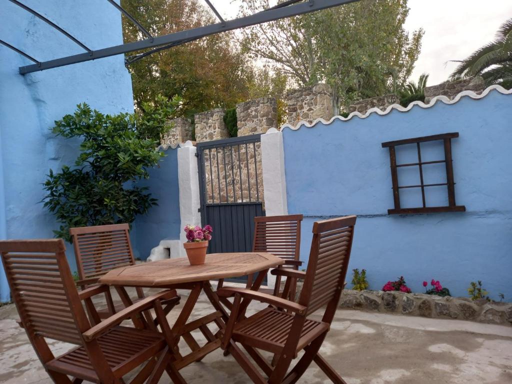 uma mesa de madeira e cadeiras em frente a uma parede azul em Casa Rural Las Raíces, Sierra de San Vicente em San Román