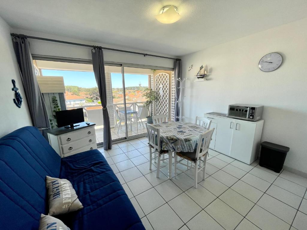 a living room with a blue couch and a table at Le Surf in Mimizan-Plage