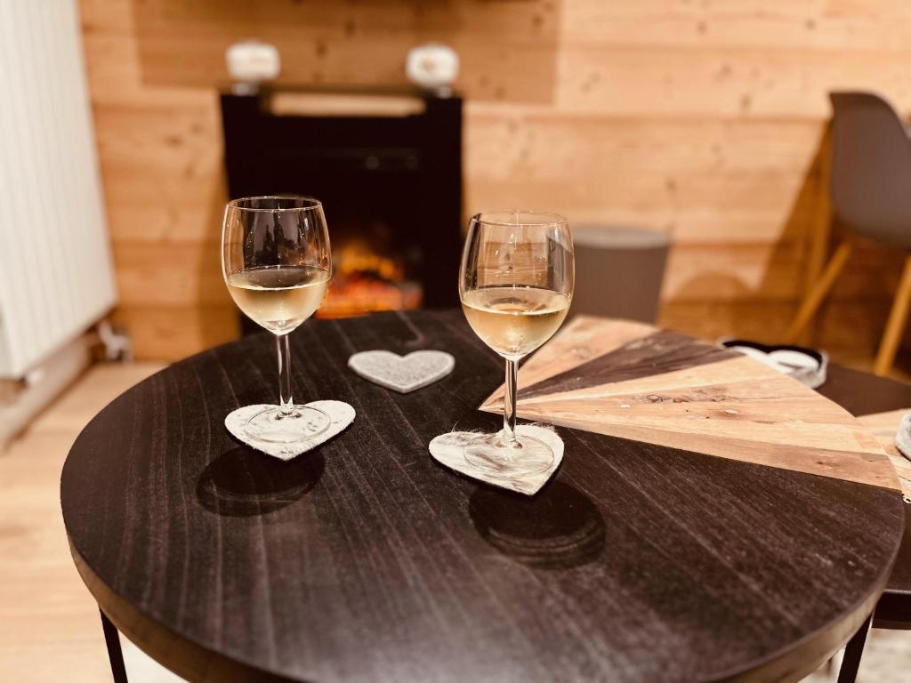 two glasses of white wine sitting on a table at Appart au centre de la station, entièrement rénové, , parking privé et wifi gratuit in Les Deux Alpes