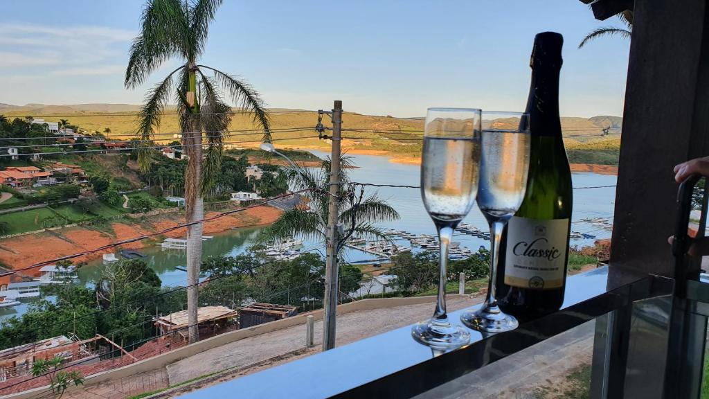 two champagne glasses on a balcony with a view of a river at Hotel Escarpas do Lago Capitolio in Capitólio