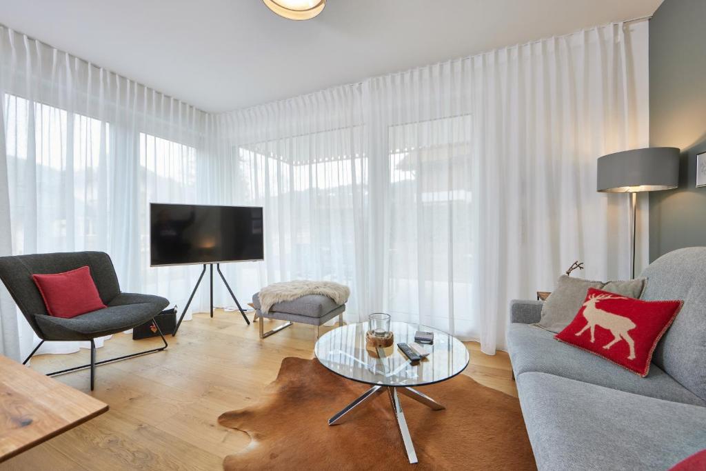 sala de estar con sofá, sillas y TV en BergZeit, en Garmisch-Partenkirchen
