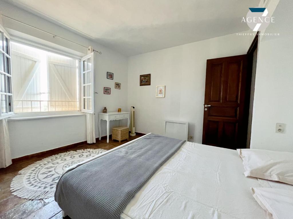 a bedroom with a large bed and a window at Le Tropezien in Grimaud