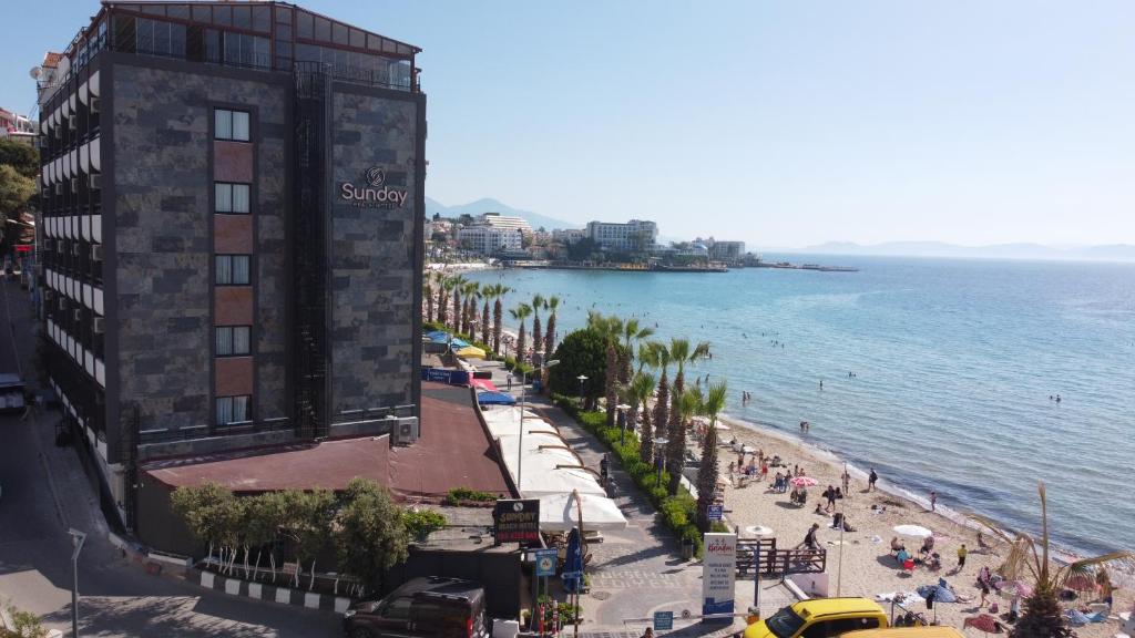 a view of a beach with a building and the ocean at Hotel Sunday Beach in Kuşadası