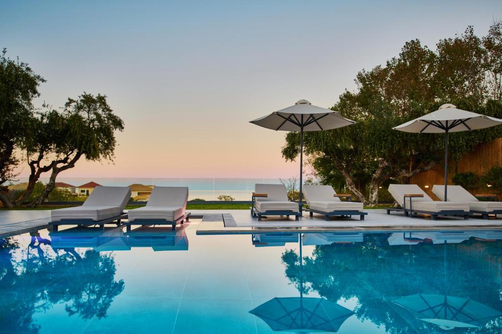 - une piscine avec des chaises et des parasols à côté de l'océan dans l'établissement Villa Belen, à Kypseli
