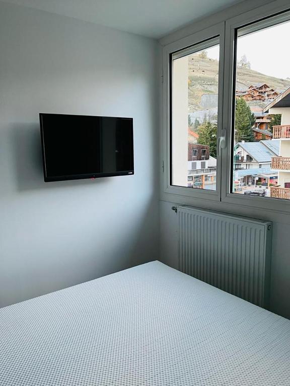 a bedroom with a flat screen tv and a bed at Appart au centre de la station, entièrement rénové, , parking privé et wifi gratuit in Les Deux Alpes