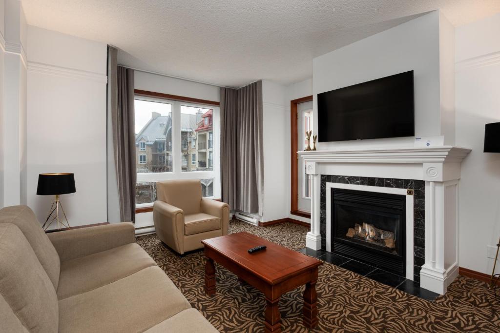 a living room with a couch and a fireplace at Sommet Des Neiges in Mont-Tremblant