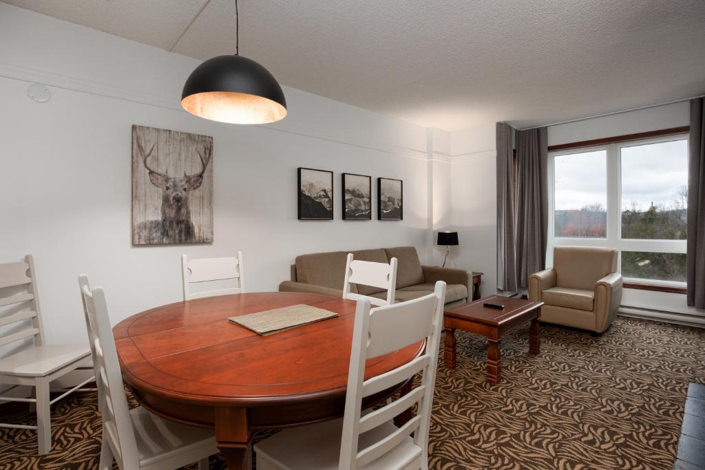 a living room with a wooden table and a dining room at Sommet Des Neiges in Mont-Tremblant