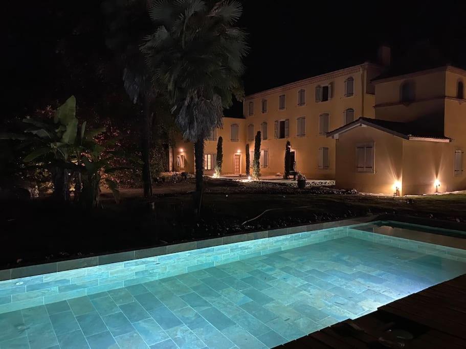 una piscina frente a una casa por la noche en Domaine des Airs de Toscane, en Cazères