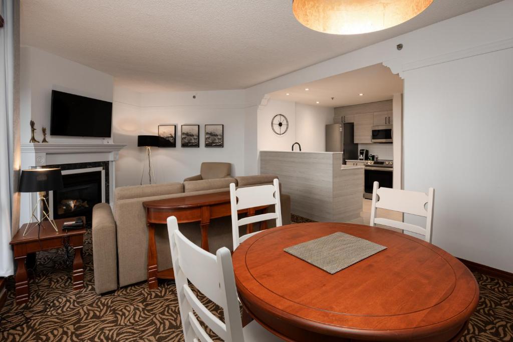 a living room with a dining room table and a kitchen at Sommet Des Neiges in Mont-Tremblant