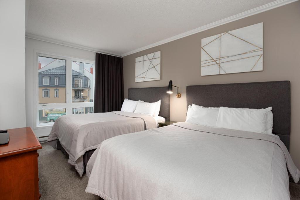 a hotel room with two beds and two windows at Sommet Des Neiges in Mont-Tremblant